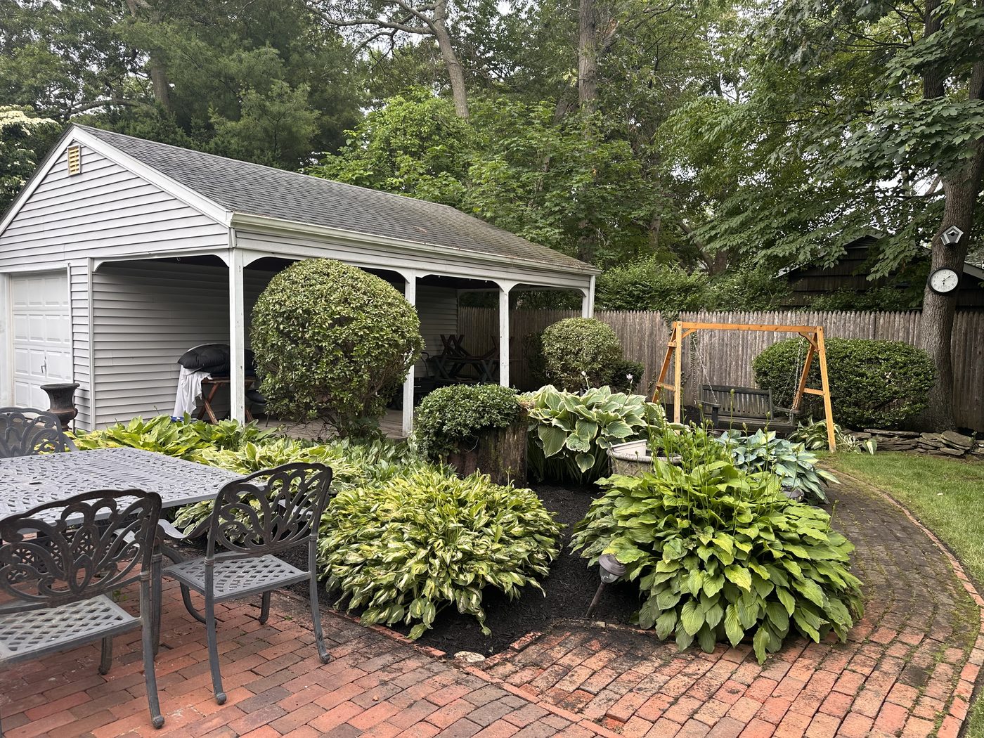 Backyard hosta garden beds, shaped shrubs, and brick patio installed by S&D Chem-Rite Lawn Care in Suffolk County, NY